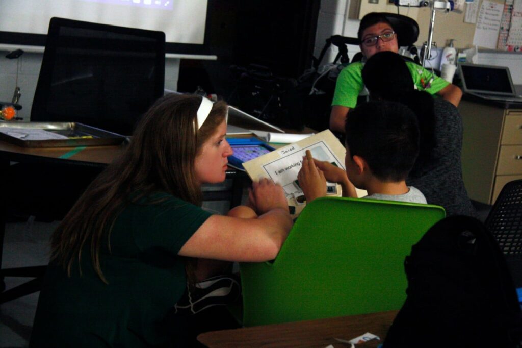 Abbey -1 - Building Wings A teacher reads a book with a student in a classroom at MacArther Middle School.