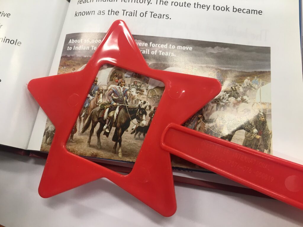 Page out of the Readtopia Westward Expansion Thematic Unit with a star shaped red magnifying glass over a picture of an Indian chief