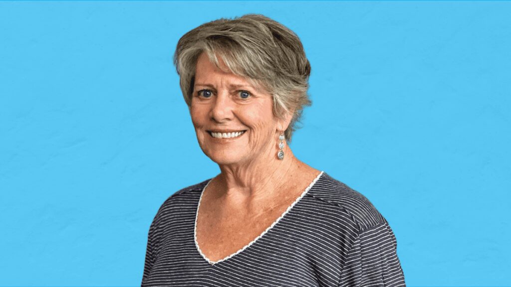 Mary Krenz on Blue Background (1) - Building Wings A woman, Mary Krenz, facing the camera with a blue background