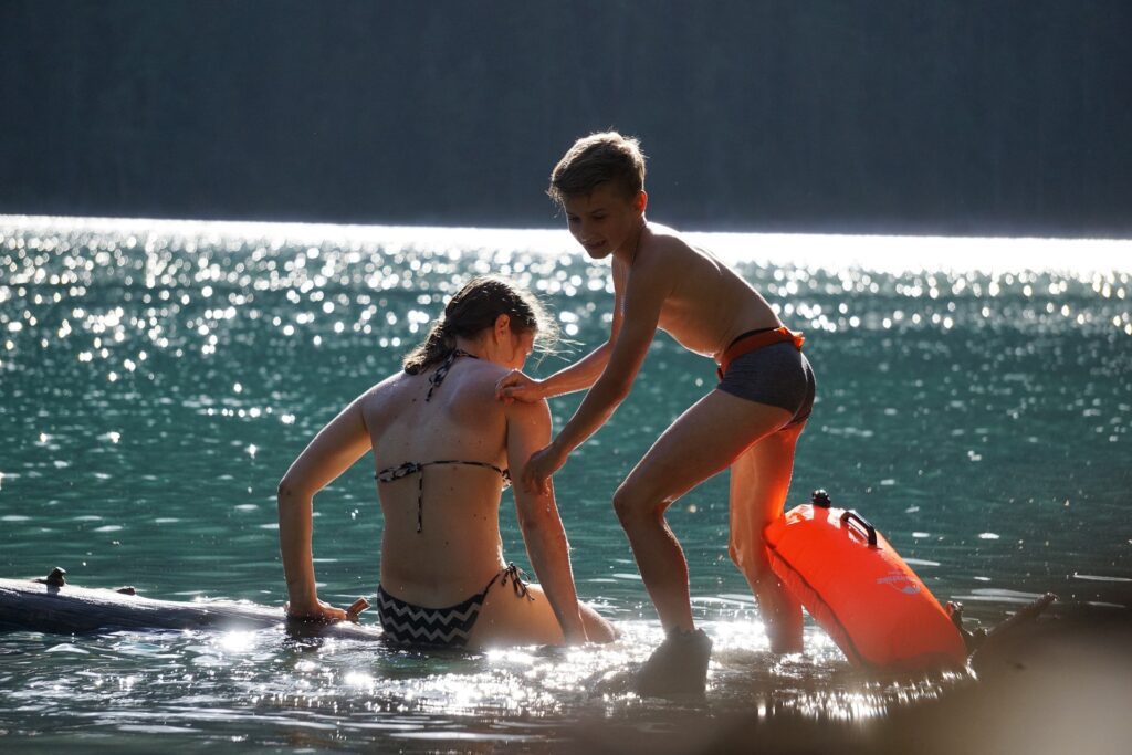 water scene with one child helping another child onto a raft - Building Wings