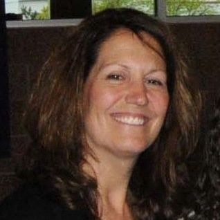 Photo of a woman with shoulder-length wavy brown hair smiling toward the camera