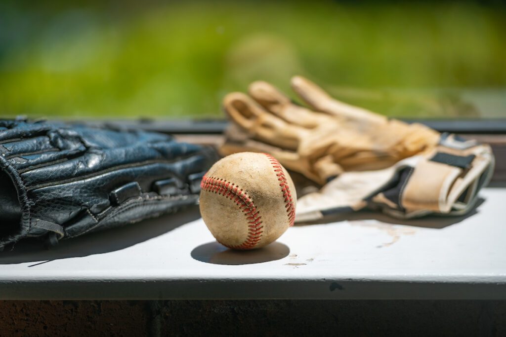 Old baseball ball mitt and batting gloves copy space - Building Wings A baseball and several baseball mitts that students can touch and feel when gaining background knowledge about baseball using a multimodal learning approach.