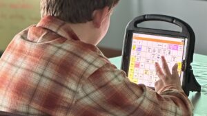 Student using an AAC communication device during literacy instruction.